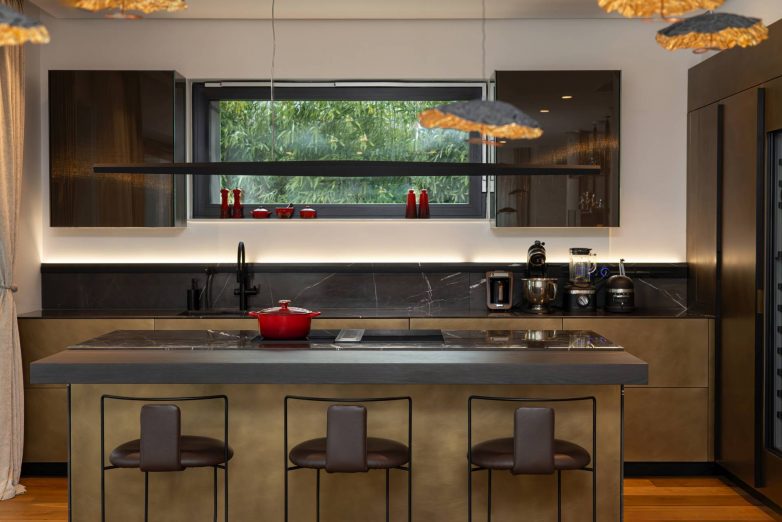 Kuhinja luksuznog stana u Beogradu sa kuhinjskim ostrvom, tamnim frontovima, crnim radnim pločama i visećom rasvetom