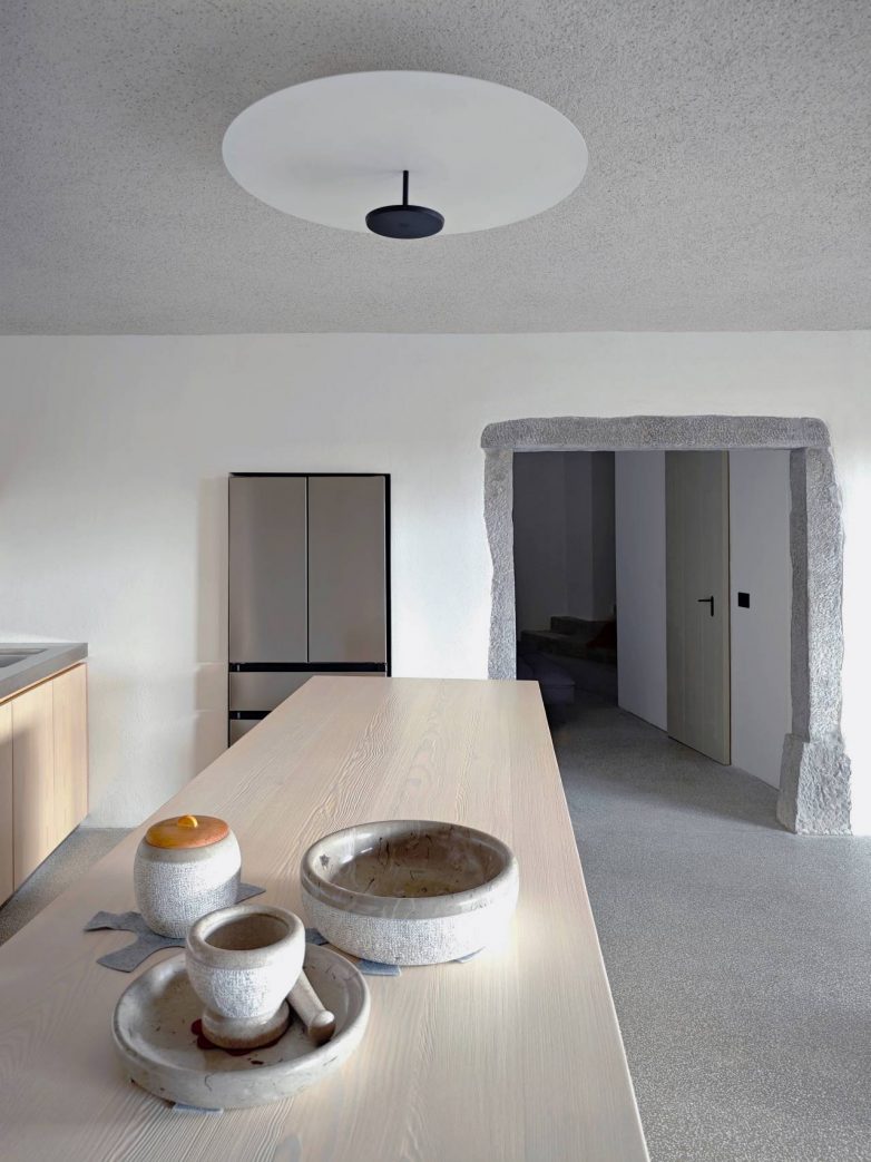 Kuhinja u kući u Sloveniji sa minimalističkim enterijerom i kamenim detaljima