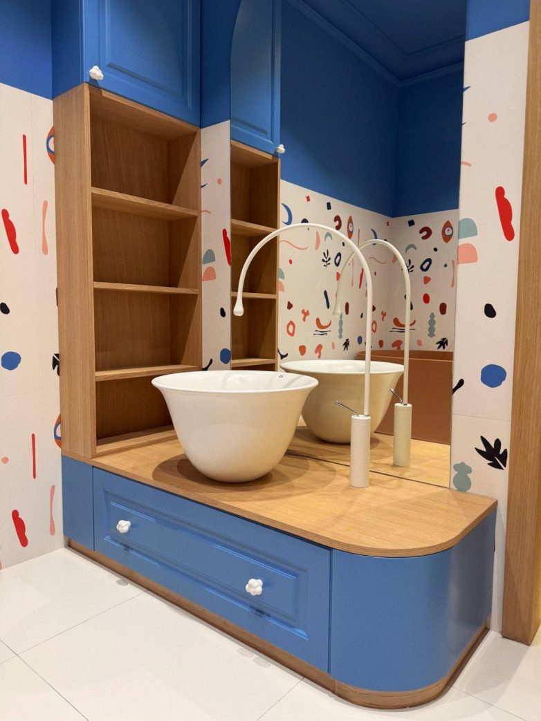 Dečje kupatilo sa plavim ormarićima, drvenom radnom pločom i lavaboom ispred ogledala