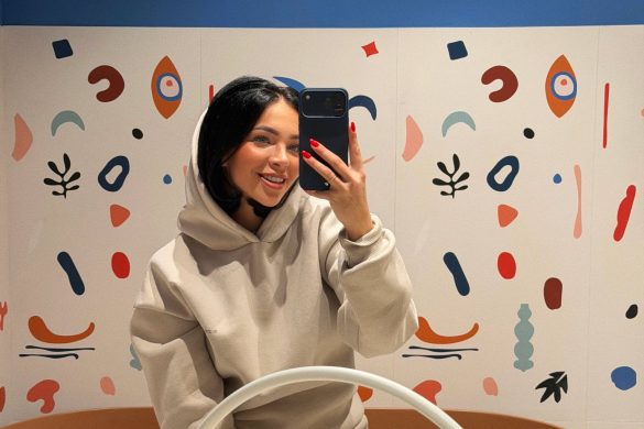 Dizajnerka u ogledalu dečjeg kupatila sa razigranim zidnim ilustracijama i apstraktnim motivima