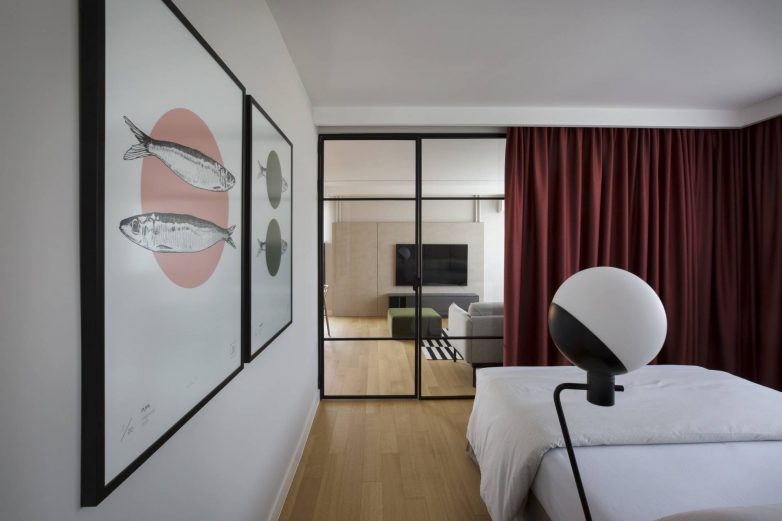 Spavaća soba u stanu u Beogradu odvojena staklenim zidom sa zavesom i pogledom ka dnevnoj zoni