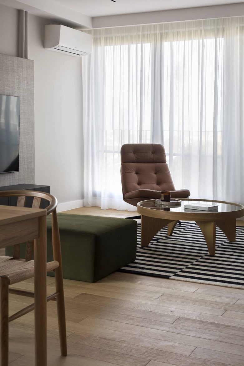 Akcentna kožna fotelja i zeleni tabure u dnevnoj zoni savremenog stana u Beogradu