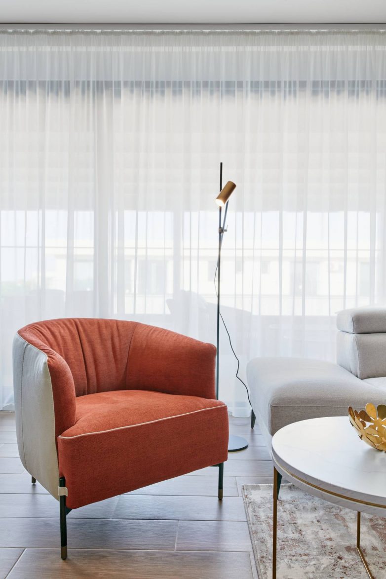 Detalj dnevnog boravka u stanu u Zrenjaninu sa "lounge" foteljom u terakota nijansi i podnom lampom