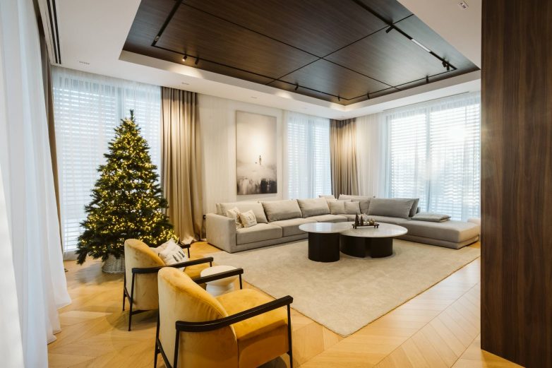 Dnevni boravak porodične kuće u Subotici sa ugaonom garniturom, drvenim plafonom, neutralnim tonovima i slojevitom rasvetom