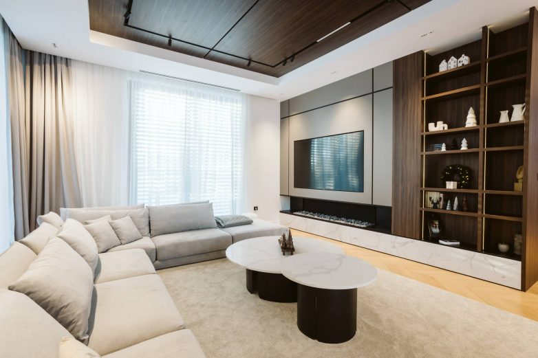 TV zid i ugradne police u dnevnom boravku porodične kuće u Subotici, sa kombinacijom drveta, mermera i integrisane rasvete