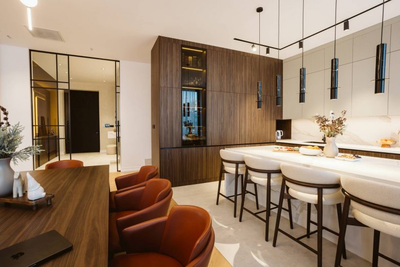 Kuhinja sa ostrvom i trpezarija u porodičnoj kući u Subotici, sa drvenim frontovima, mermernom radnom pločom i visećom rasvetom