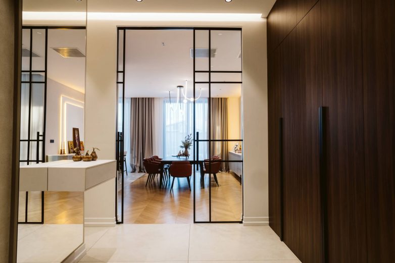 Ulazni prostor porodične kuće u Srbiji sa kliznim staklenim vratima, drvenim ormarima i otvorenom vizurom ka trpezariji