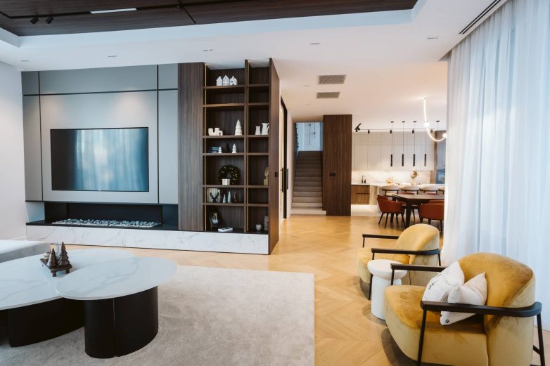 Otvoreni dnevni boravak porodične kuće u Srbiji sa TV zidom, ugradnim policama i vizurom ka trpezariji i kuhinji