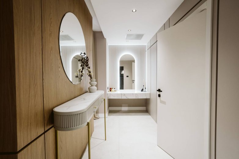 Garderobni i toaletni prostor porodične kuće u Srbiji sa drvenim frontovima, ovalnim ogledalom i konzolnim toaletnim stolom