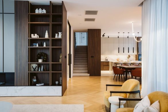 Otvoreni dnevni boravak i trpezarija porodične kuće u Srbiji sa drvenim policama, kliznim vratima i toplom neutralnom paletom