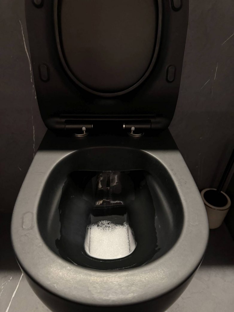 Tragovi kamenca i vode na crnoj WC šolji u kupatilu, vidljivi u svakodnevnoj upotrebi