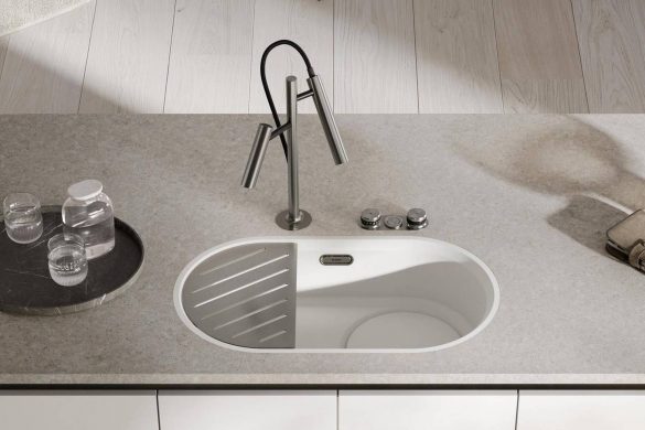 Podgradna ovalna sudopera BLANCO Oovalon u beloj boji, ugrađena u sivu radnu ploču sa dizajnerskom slavinom