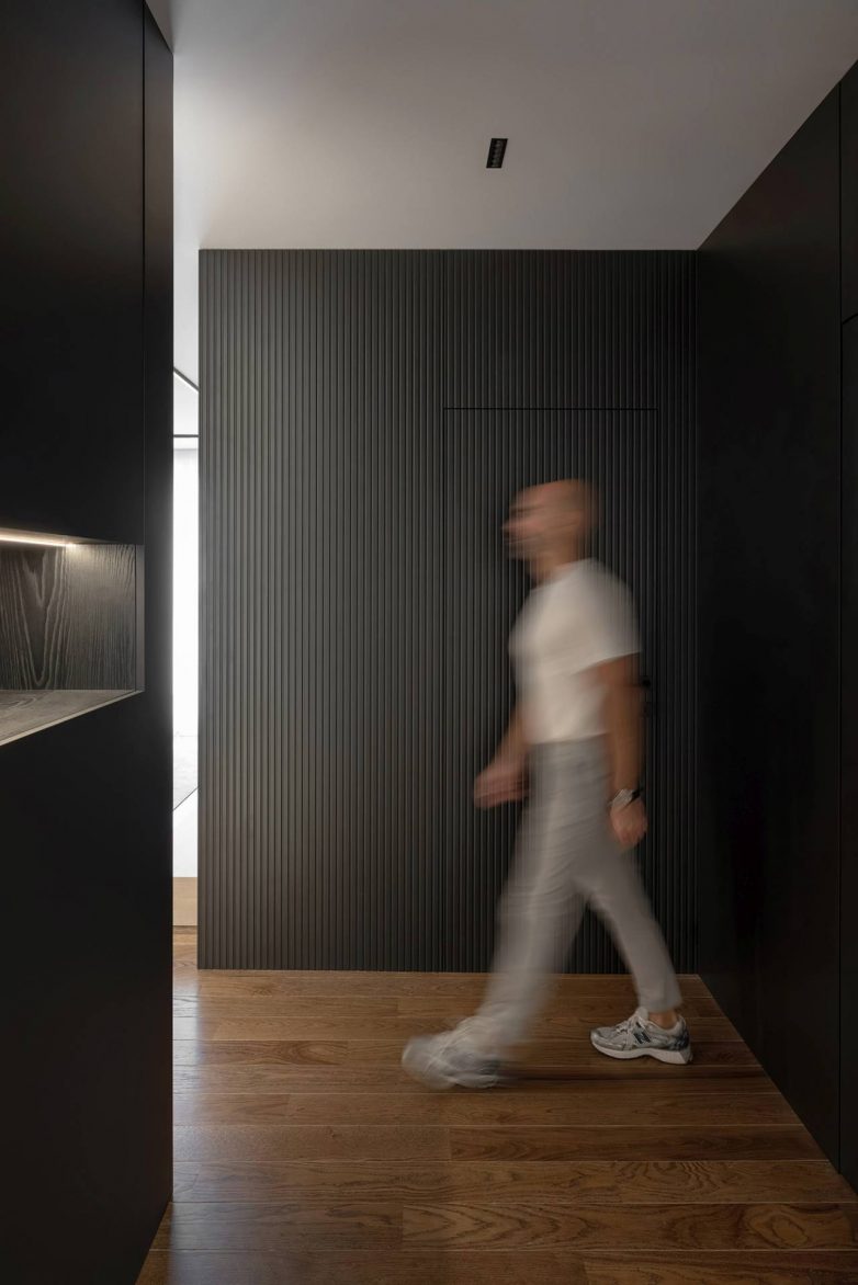 Ulazna zona stana od 60 kvadrata u Nišu sa tamnim vertikalnim zidnim oblogama i skrivenim vratima