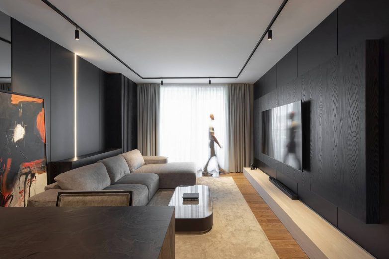 Dnevni boravak stana od 60 kvadrata u Nišu sa tamnim zidnim oblogama, sivom garniturom i ugradnom rasvetom