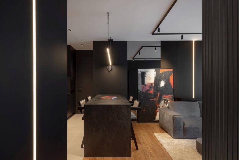 Trpezarijski sto u stanu od 60 kvadrata u Nišu sa tamnim zidnim oblogama, umetničkom slikom i linearnom rasvetom