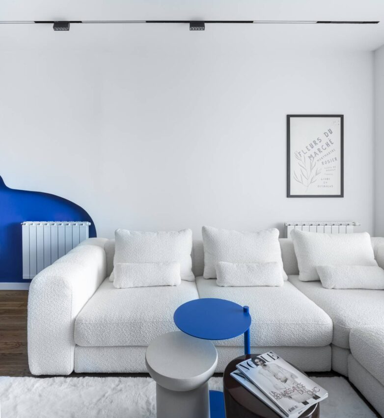 Dnevna soba stana u Banja Luci sa belom modularnom garniturom, plavim stočićem i indigo zidom u pozadini