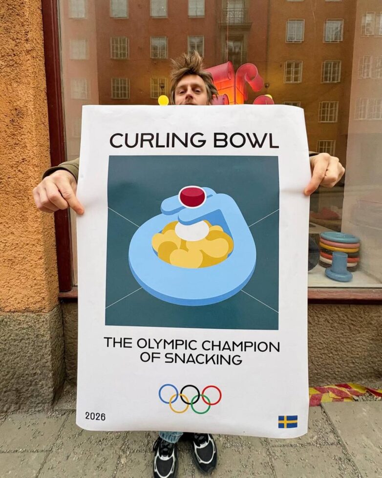Gustaf Vestman drži poster Curling Bowl sa ilustracijom činije inspirisane karlingom i natpisom Olympic Champion of Snacking