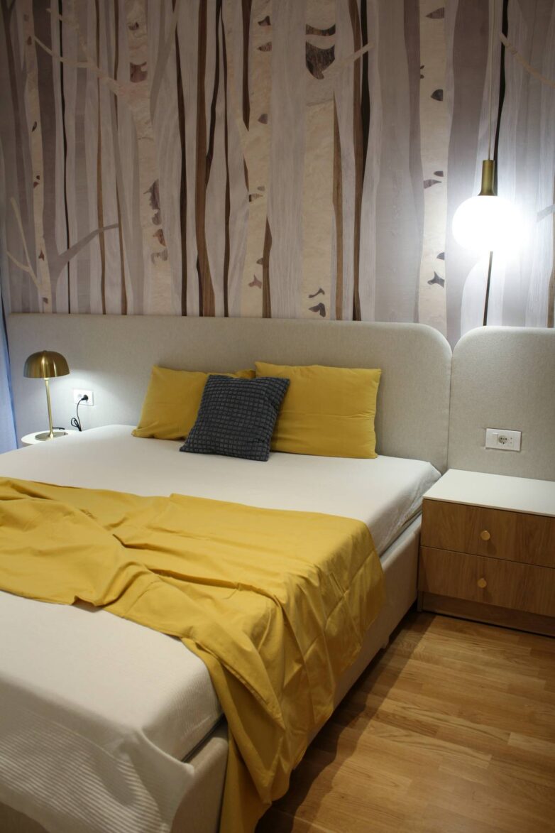 Spavaća soba u stanu od 38 m2 u Novom Sadu sa tapetom, dugim uzglavljem i žutim akcentima