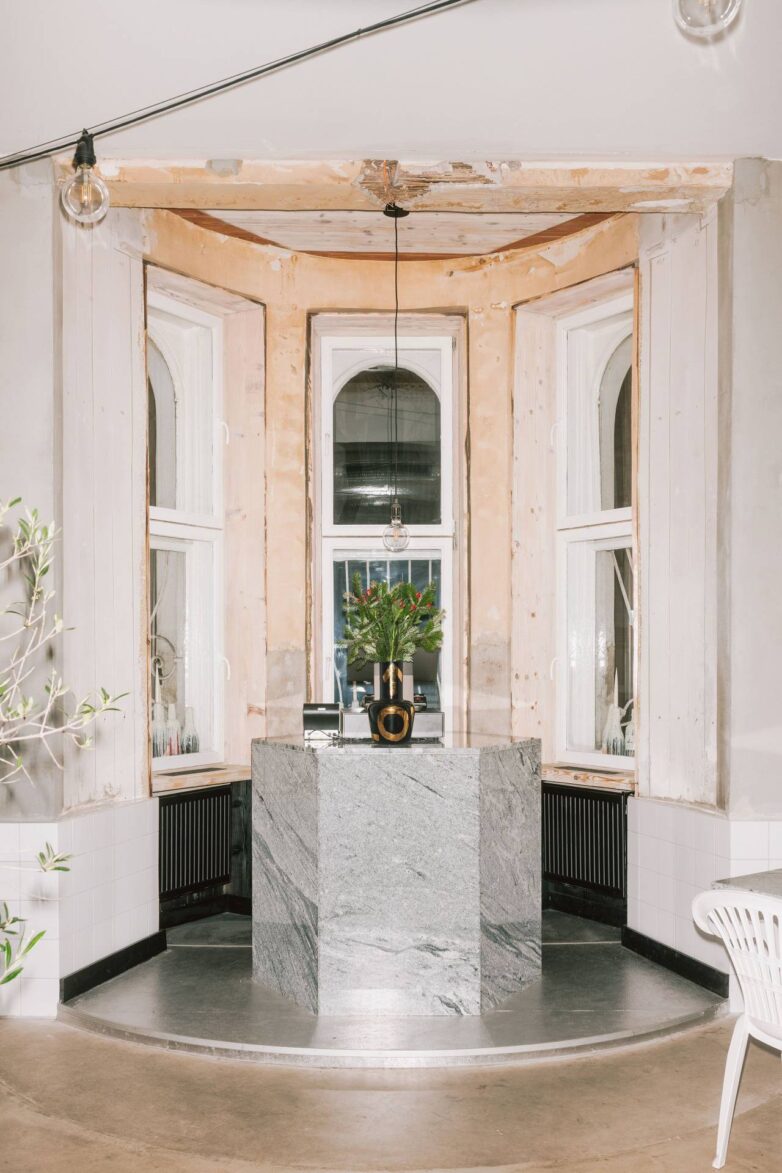 Mermerni centralni pult u enterijeru picerije Oli's Italiano u Bratislavi sa visokim prozorima i ogoljenim zidovima