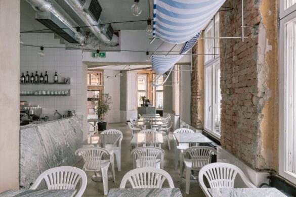 Enterijer picerije Oli's Italiano u Bratislavi sa belim Monobloc stolicama, mermernim stolovima, prugastim tendama i ogoljenim zidom od cigle