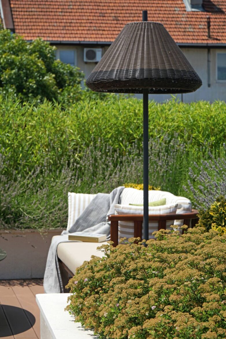 Podna lampa od pletenog materijala na terasi u Valjevu, uz "lounge" garnituru i gusto zelenilo