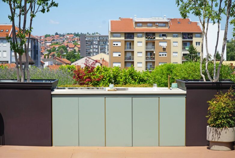 Spoljna kuhinja sa sudoperom i skladišnim elementima na krovnoj terasi u Valjevu, sa pogledom na gradske krovove