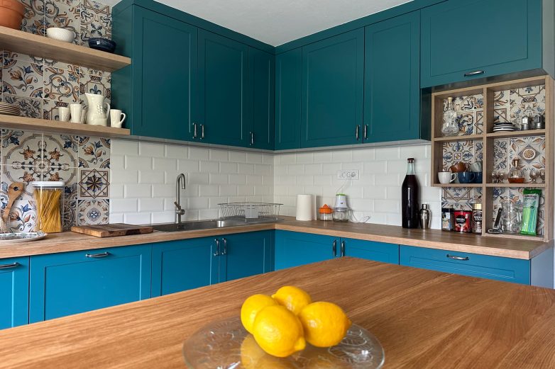 Detalj kuhinje sa tirkiznim frontovima, drvenom radnom pločom, sudoperom i kombinacijom dekorativnih i belih "subway" pločica