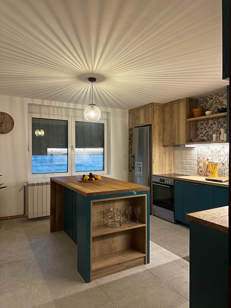 Kuhinja sa drvenim kuhinjskim ostrvom, tirkiznim frontovima i visilicom koja stvara efektne senke na plafonu