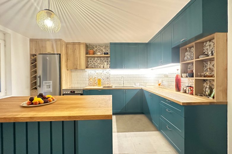 Kuhinja u L rasporedu sa tirkiznim frontovima, drvenom radnom pločom, LED osvetljenjem i kombinacijom dekorativnih i "subway" pločica