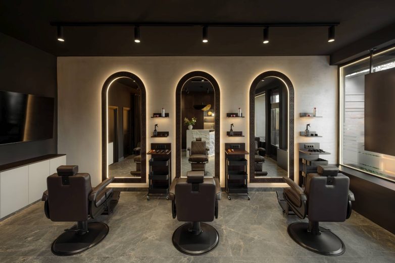 Radna zona frizerskog salona sa tri ogledala, stolicama i toplim osvetljenjem