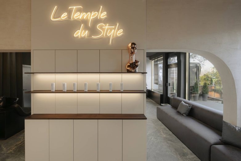 Čekaonica frizerskog salona L'Atelier 35 sa neonskim natpisom i policama za proizvode