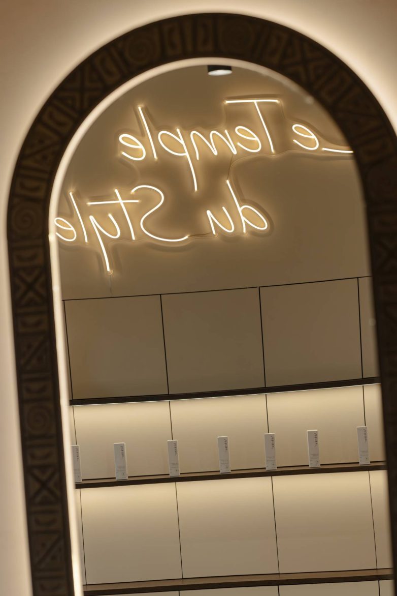 Ogledalo sa reljefnim okvirom i neonskim natpisom u enterijeru frizerskog salona