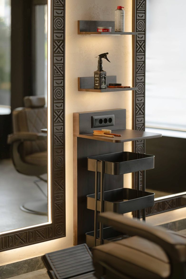 Detalj radne stanice u frizerskom salonu sa ogledalom, policama i opremom za rad