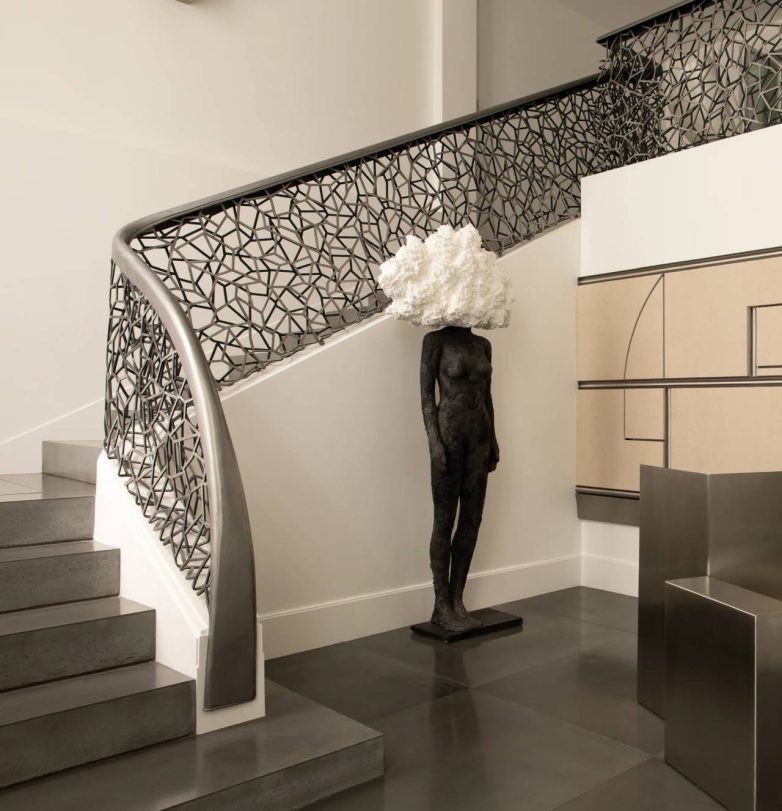 Detalj stepeništa sa perforiranom metalnom ogradom i skulpturom u enterijeru Karla Lagerfelda