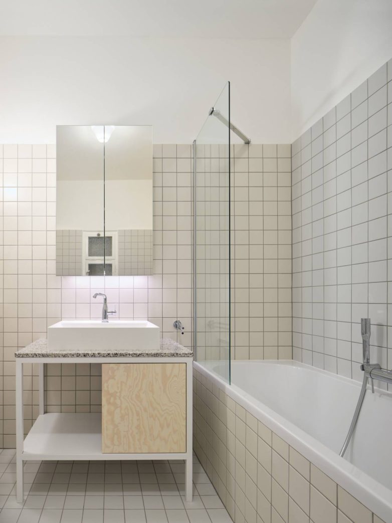 Kupatilo sa sitnim keramičkim pločicama, kadom i umivaonikom na granitnoj ploči u stanu u Pragu