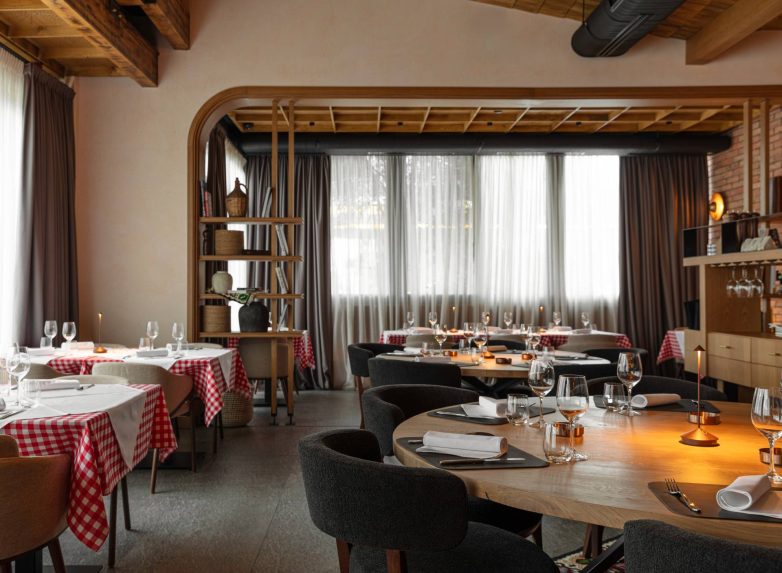 Trpezarijski prostor restorana Stena u Beogradu sa drvenim stolovima, kariranim stolnjacima i velikim prozorima