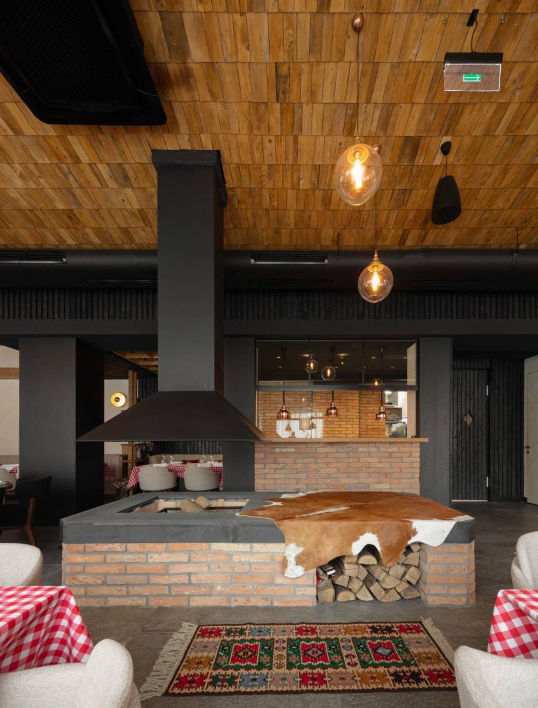 Centralno ložište od opeke u restoranu Stena u Beogradu sa drvenim plafonom i visećom metalnom haubom