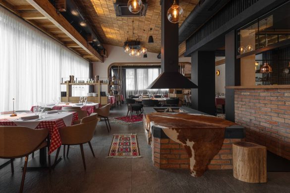 Enterijer restorana Stena u Beogradu sa centralnim ložištem, opekom, drvenim plafonom i stolovima sa kariranim stolnjacima