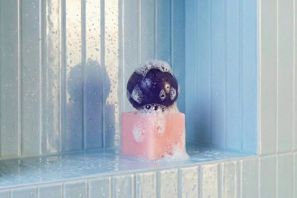 Skulpturalni sapun sa ljubičastom sferom i roze kockom u tuš niši sa svetloplavim pločicama