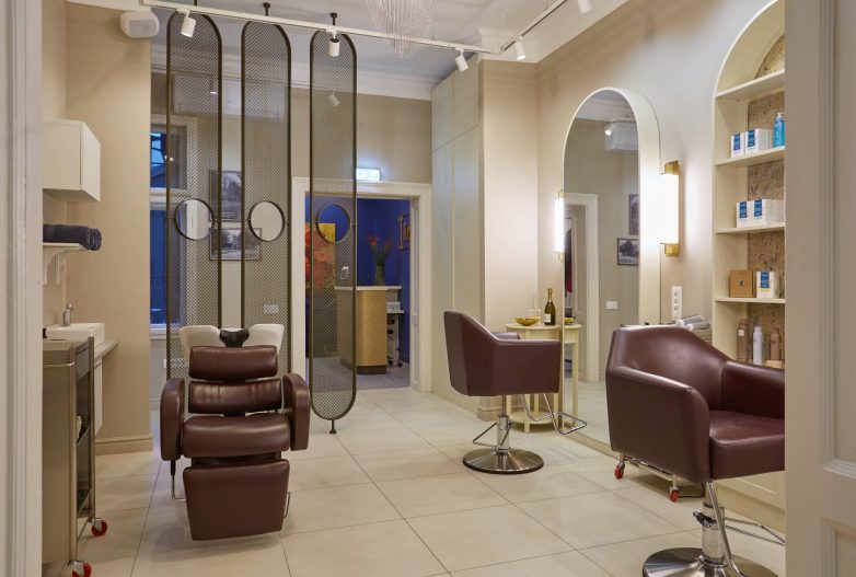 Enterijer spa salona IZIZI u Beogradu sa frizerskim stolicama i dekorativnim metalnim paravanima