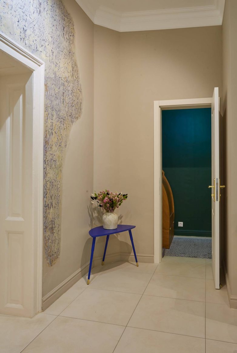 Detalj enterijera spa salona IZIZI u Beogradu sa očuvanim istorijskim slojevima zida i plavim stočićem