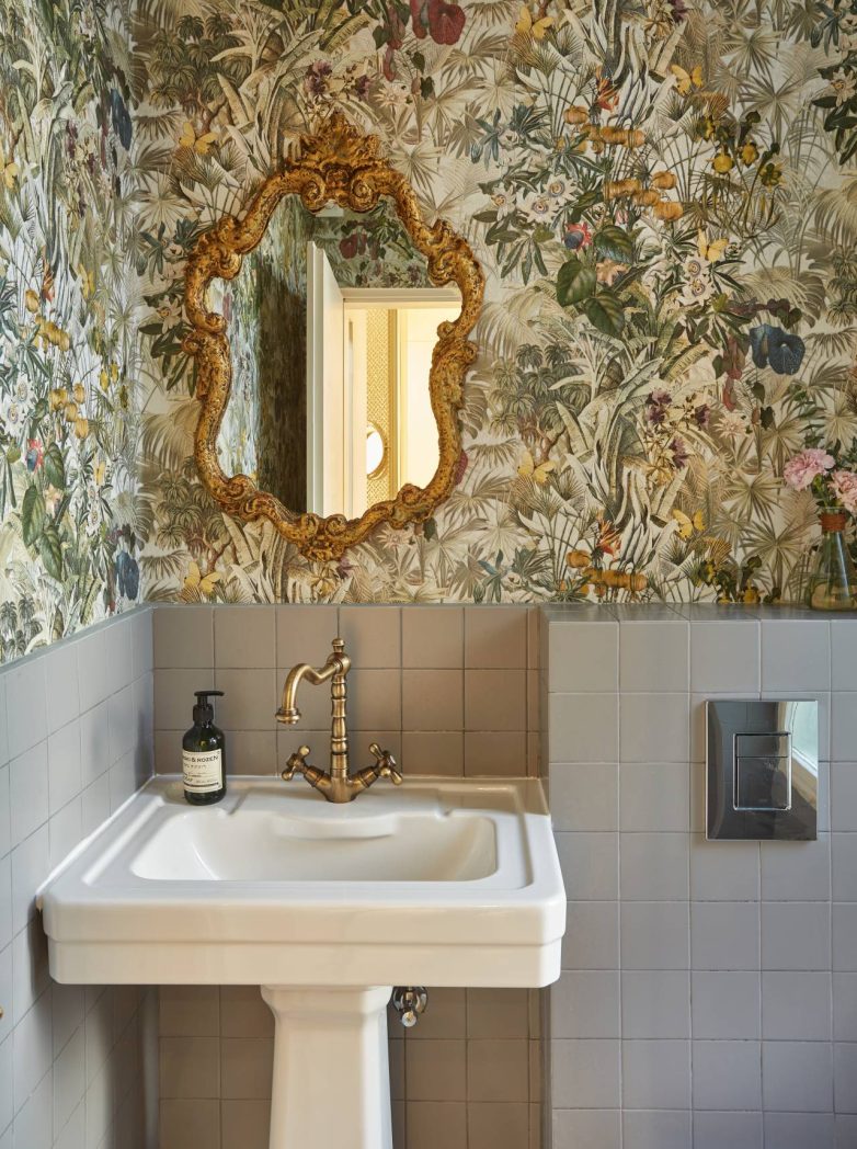 Kupatilo u spa salonu IZIZI u Beogradu sa dekorativnom tapetom i zlatnim ogledalom