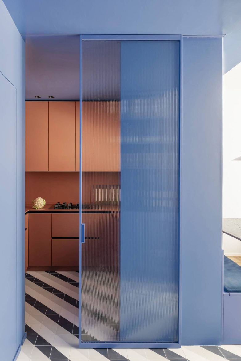 Kuhinja u stanu u Milanu sa terakota elementima i plavim kliznim vratima od rebrastog stakla