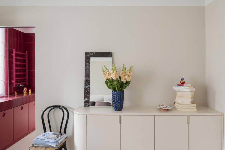 Komoda u neutralnim tonovima u stanu u Milanu sa pogledom na kupatilo obloženo crvenim pločicama