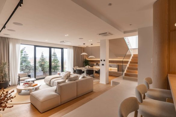 Otvoren dnevni prostor sa garniturom, trpezarijom i velikim staklenim zidovima koji gledaju ka šumi u kući u Raniloviću