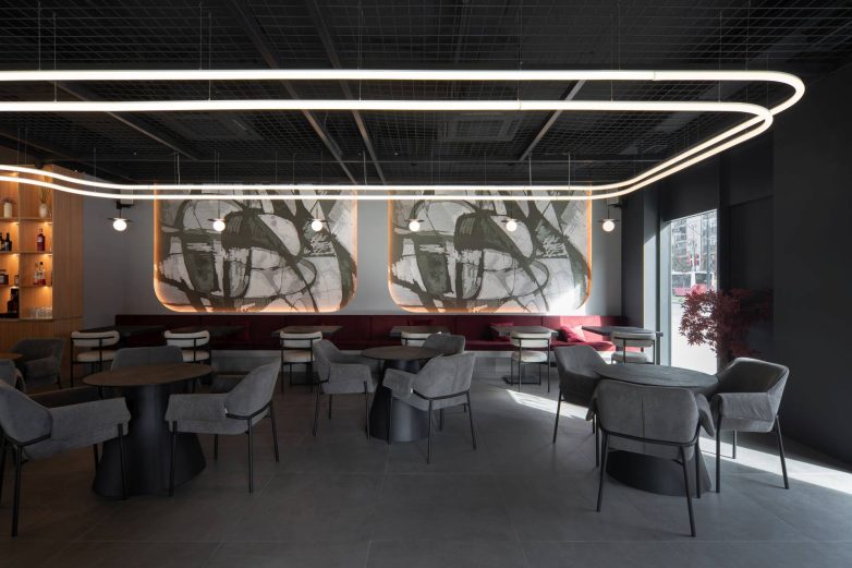 Zona sedenja u baru u Beogradu sa stolovima, tapaciranim klupama i dekorativnim zidnim panelima