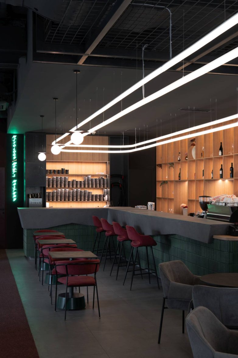 Šank u baru u Beogradu sa barskim stolicama, drvenim policama i linearnom svetlosnom instalacijom