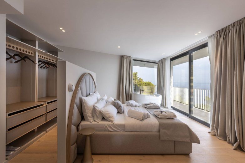 Spavaća soba u vili Vinea Privata na Hvaru sa velikim staklenim vratima, pogledom na more i kadom pored prozora