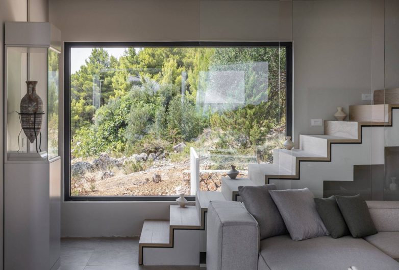 Minimalističko stepenište i veliki panoramski prozor u enterijeru vile Vinea Privata na Hvaru sa pogledom na borove i mediteransko rastinje