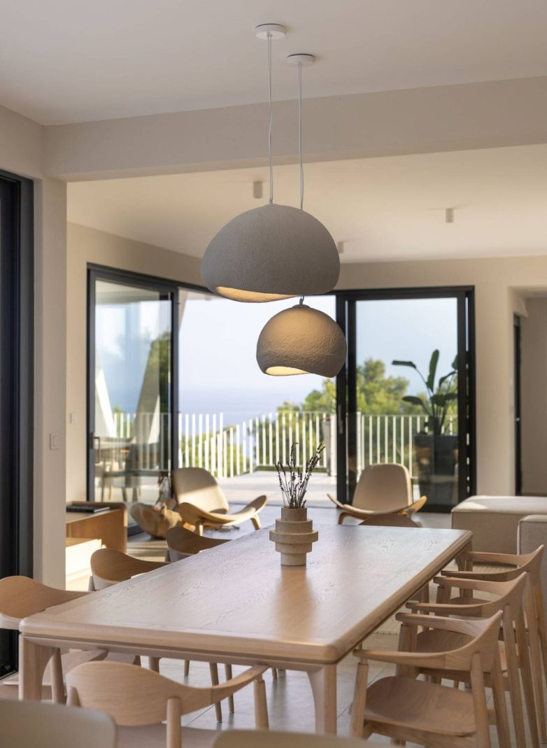 Drvena trpezarija u enterijeru vile Vinea Privata na Hvaru sa visećim lampama i pogledom na terasu i more